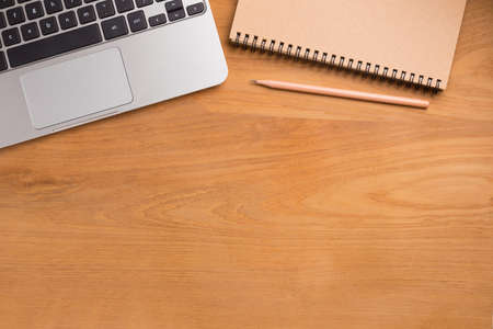 Portable computer laptop, pencil, paper notebook on wooden table