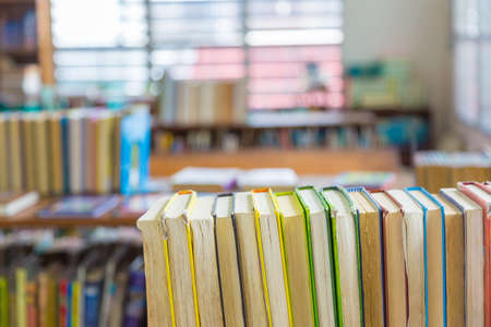 Hard covered library books line up on a shelf, selective focus with blurred backgroundの写真素材
