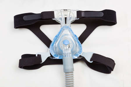 Sleep apnea CPAP mask and hose on white pillow background, to use with CPAP machine for people with...