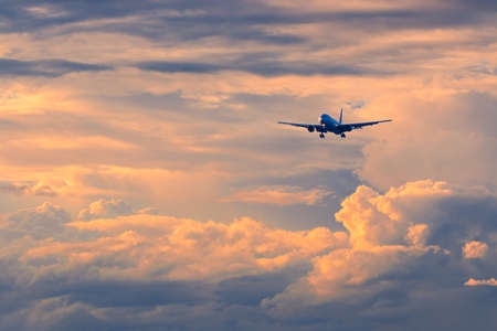 Commercial passenger airplane coming in for landing against beautiful colorful sunset, color and...