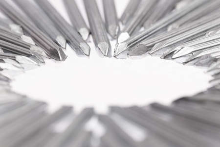Steel concrete nails pointing the tips toward empty white space for text in the center of the white...