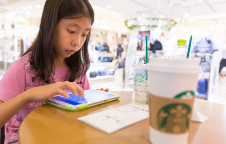 TOKYO, JAPAN - 17 JULY 2016 - Asian girl uses computer tablet at Starbucks Coffee shop in a shopping...