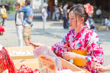 KAWAGOE, JAPAN - 20 JULY 2016 - Japanese woman in yugata, traditional japanese dress, try her luck by baiting lucky fortune paper fish form the piles at Hikawa Shrine in Kawagoe town, Japan on July 20, 2016.のeditorial素材