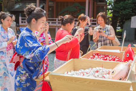 KAWAGOE, JAPAN - 20 JULY 2016 - Japanese and Asian tourists try their luck by baiting lucky fortune paper fish form the piles at Hikawa Shrine in Kawagoe town, Japan on July 20, 2016.のeditorial素材