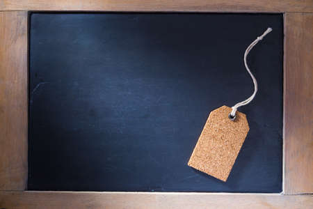 Single cork tag on small chalkboard with lots of copy space, hard side lighting for dramatic and retro feelの写真素材
