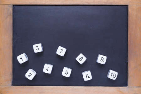 White number dices on small wooden framed chalkboard, copyspace for text on top section, good for...