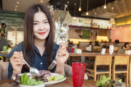 happy young asian woman smiling at camera having healthy lunchの写真素材