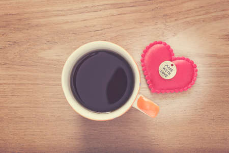 felt heart with Made With Love button and cup of coffee on wooded table, good for valentine or special occasionの写真素材