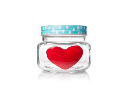 red felt heart in glass jar with blue poka dot lid, isolated white background with copyspaceの写真素材