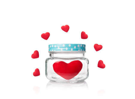 valentine and love theme, big red felt heart in glass jar with blue poka dot lid surrounded by small red hearts, isolated white backgroundの写真素材