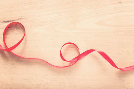 strip of red ribbon on wood background with vintage color tone with copy space