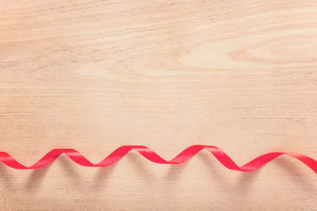 strip of red ribbon on wood background with vintage color tone with copy spaceの写真素材