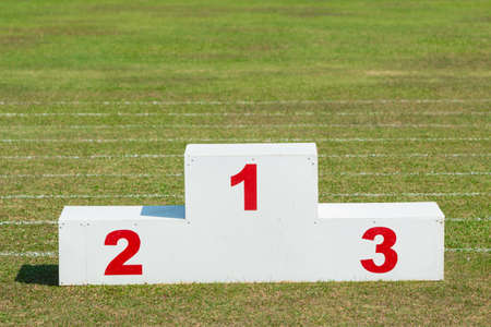 white wooden sport award stand with red numbers, outdoor in the sport field on a sunny dayの写真素材