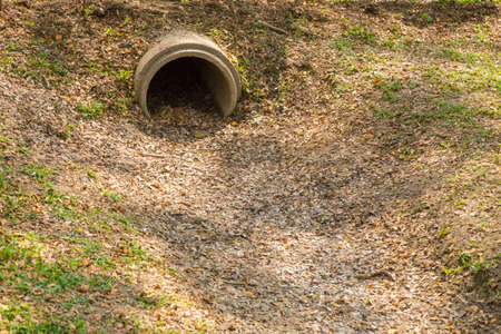 dry drainage pipe with fallen leaves, showing danger sign of drought and shortage of waterの写真素材