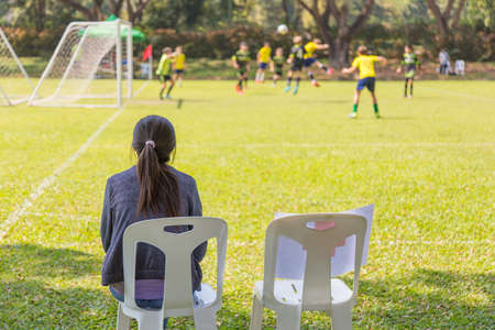 woman watching a school boy soccer game on a sunny dayの写真素材