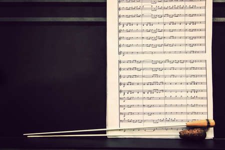music sheets and conductor's batons on black metal stand in warm retro color tone, with room for copy spaceの写真素材