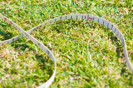 close up of sport measuring tape on grassy field showing 1 meter mark, on sunny dayの写真素材