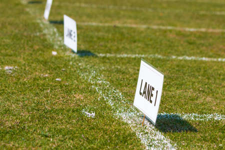Lane signs on grass field for elementary school track and field tournamentの写真素材