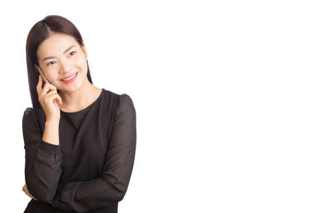 asian young happy smiling woman in black dress, talking on her cellphone, white background, room for copy spaceの写真素材