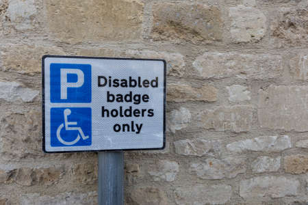 disabled or handicapped badge holder parking sign, against stone wall