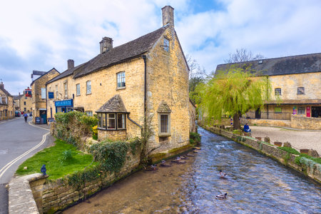 Bourton On The Water, England - 7 April 2017 - Old stone buildings stand along a river at Bourton On The Water, England on April 7th, 2017.のeditorial素材