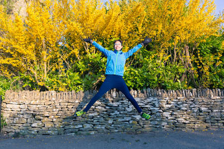 happy young asian teenager jumping with joy in one fine spring morning outside in front of beautiful...