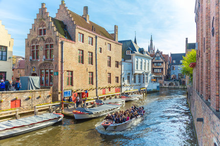 Bruges, Belgium - 11 April 2017 - Tourists enjoy their river around city tour on small tour boat on river of Bruges, Belgium on April 11, 2017のeditorial素材