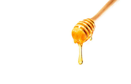 dripping honey on wooden dipper white background with room for copy space