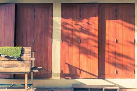 warm evening light with leaf shadow shining on old style wooden doors in vintage color tone, good for vintage themed backgroundの写真素材