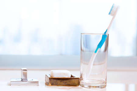 clean toothbrush in a clear glass on bathroom countertop with white soap and blurred background.Concept of heathy lifestyleの写真素材