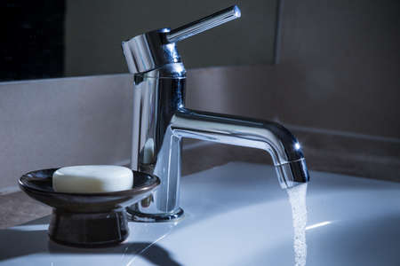 bathroom water faucet with water running at night, concept for waste resouce