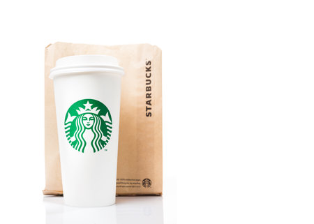 Chiang Mai, Thailand - 30 September 2017 - Starbucks white paper cup, showing the brand logo, and brown bag sit on top of white table againse white background in Chiang Mai, Thailand on September 30, 2017のeditorial素材