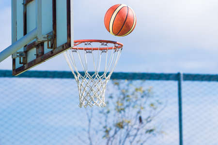 basketball floating about to get in the hoop at an outdoor basketball courtの写真素材