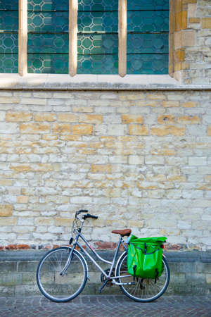 retro style bicycle parks leaning against old European church's stone wall, in morning light, good for lifestyle or transportation themeの写真素材
