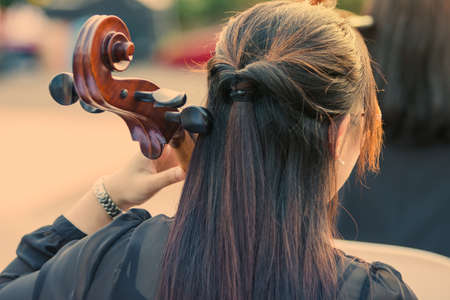 woman playing cello at an outdoor concert, during warm golden hour evening light, good for music or self interest theme conceptの写真素材