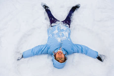 Asian female teenager enjoying herself making snow angel on a cold winter day in Japan