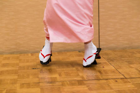 View of Japanese women legs and feet in traditioanl dancing in full traditioanl dress and Japanese style geta shoes, showing with unusual style of standing and dancing on front part of their shoesの写真素材