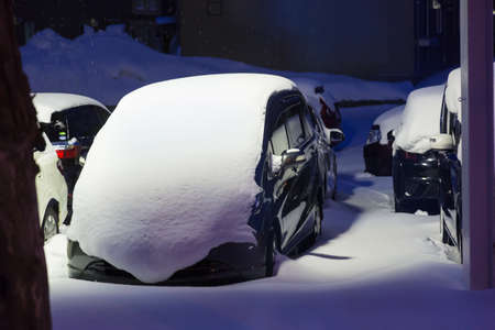 Cars covered in snow at night during cold winter in Hokkaido, Japan