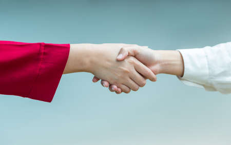 Women handshaking in agreement or friendship, good for business, friendship, or agreement concept, plain color background with room for copyspaceの写真素材