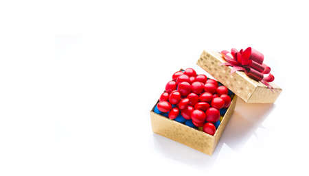 Golden color box of colorful chocolate on white background with red bow, with room for textの写真素材