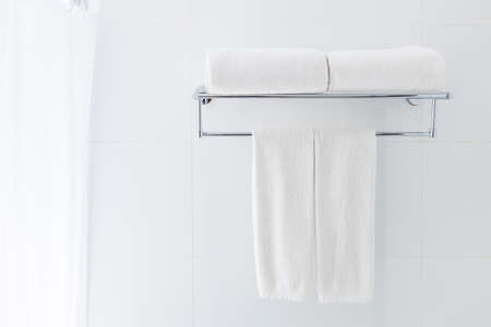 White bathroom towels hanging on the rack in a white bathroom near shower, good for clean and fresh theme or refresh conceptの写真素材