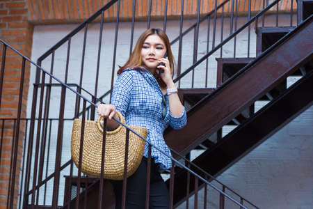 Attractive happy young asian woman going shopping walking down the stairs of a shopping plaza while...