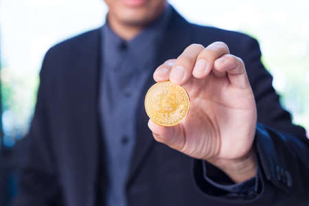Businessman holding a Bitcoin, cryptocurrency coin in his hand, selective focusの写真素材