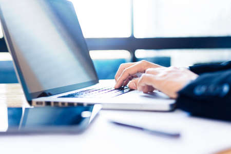 Hands of businessman working on his computer with bright light coming from window with blue color tone, good for business or technology conceptの写真素材