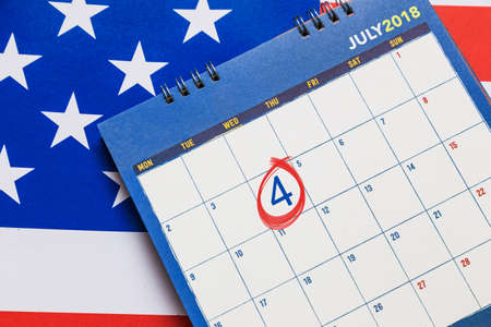 Calendar showing July month with red circle on 4th day with American flag in background, good for 4th of July themeの写真素材