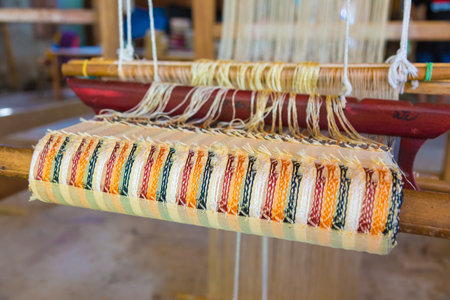 LUANG PRABANG, LAOS - 30 June 2018 - Woven fabric is partly done on hand made loom at a local shop...