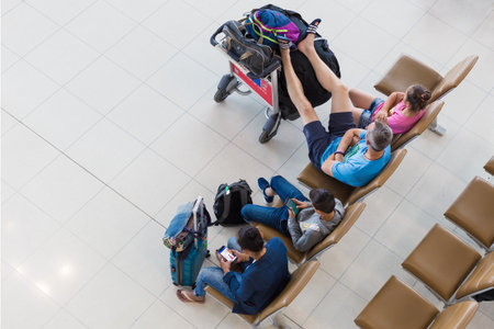 BANGKOK, THAILAND - 21 JULY 2018 - Four tourists wait casually for their flights with some use their mobile devices at Suvarnabhumi International Airport in Bangkok, Thailand on July 21, 2018のeditorial素材