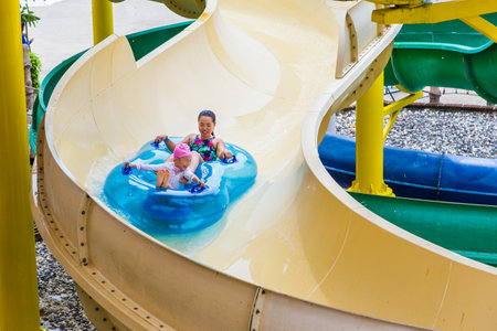 PHUKET, THAILAND - 8 JULY 2017 - Asian mom and daughter slide down water slider on double floater at Splash Jungle Water Park in Phuket, Thailand on July 8, 2017のeditorial素材