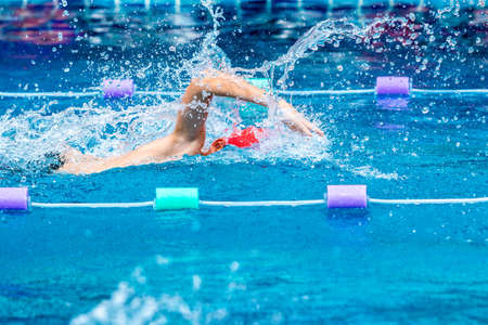 Young boy swimmer practicing hard in his freestyle stroke in a local swimming poolの写真素材