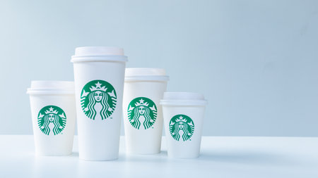 CHIANG MAI, THAILAND - 31 December 2018 - Starbucks white take home coffee cups in various sizes line up on white table against white background in Chiang Mai, Thailand on December 31, 2018のeditorial素材